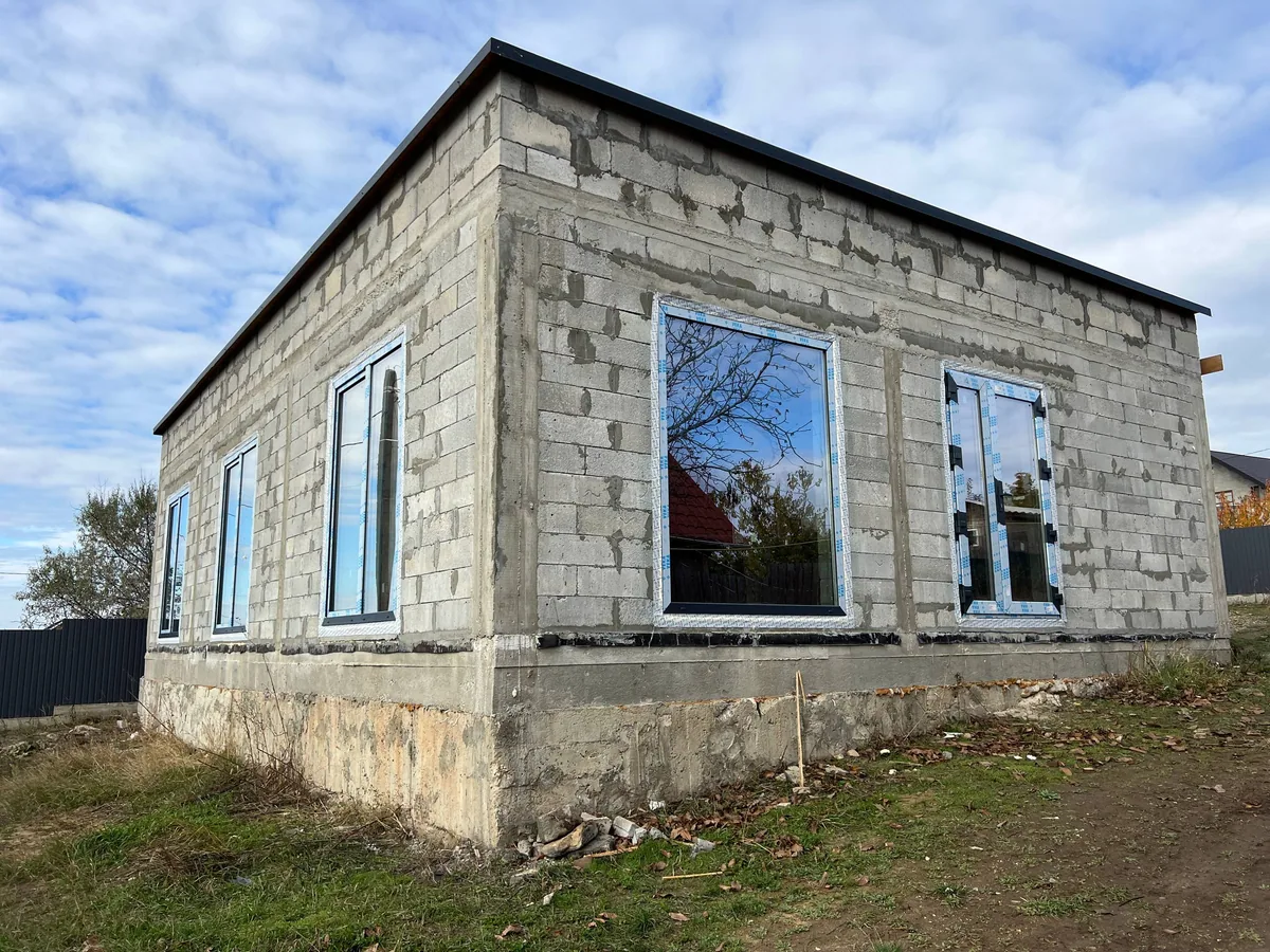 Ferestre PVC albe proaspăt montate pe o casă din blocuri de beton celular