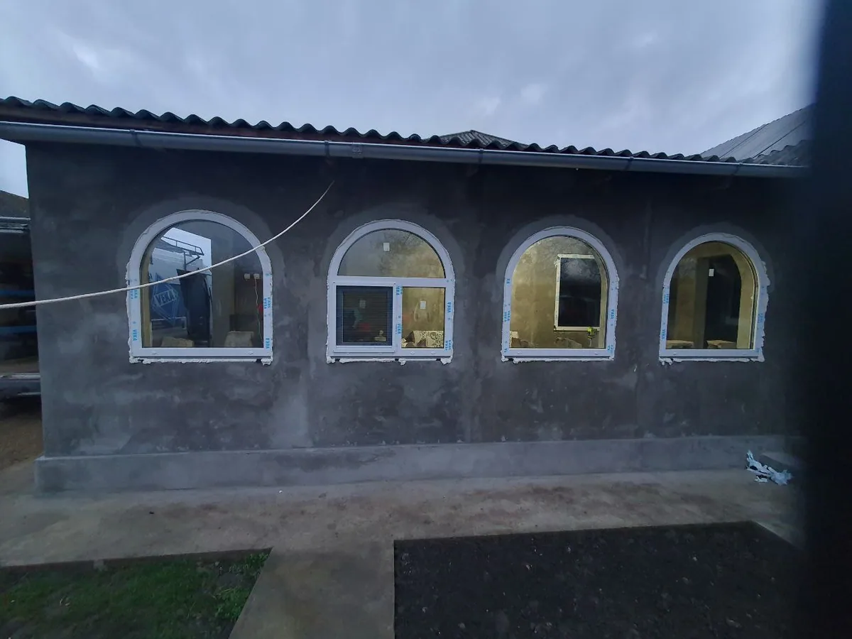 Patru ferestre PVC arcuite albe, una cu canat oscilobatant, pe fațadă gri