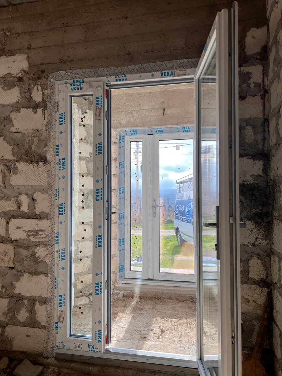 Uși PVC VEKA albe montate într-o casă nouă, cu ușă deschisă spre exterior
