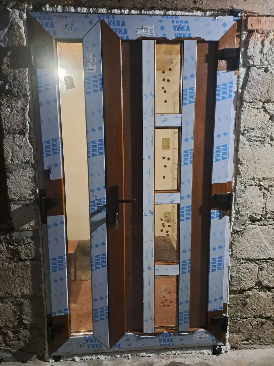 Ușă dublă PVC maro cu textură lemn și geam termopan, montaj pe șantier